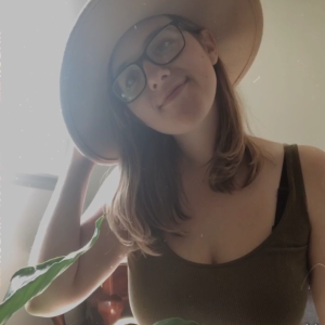 Woman in a green tank top holding her hat on her head