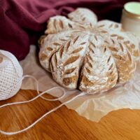 An artisan pumpkin sourdough loaf on crumpled parchment with a roll of twine,