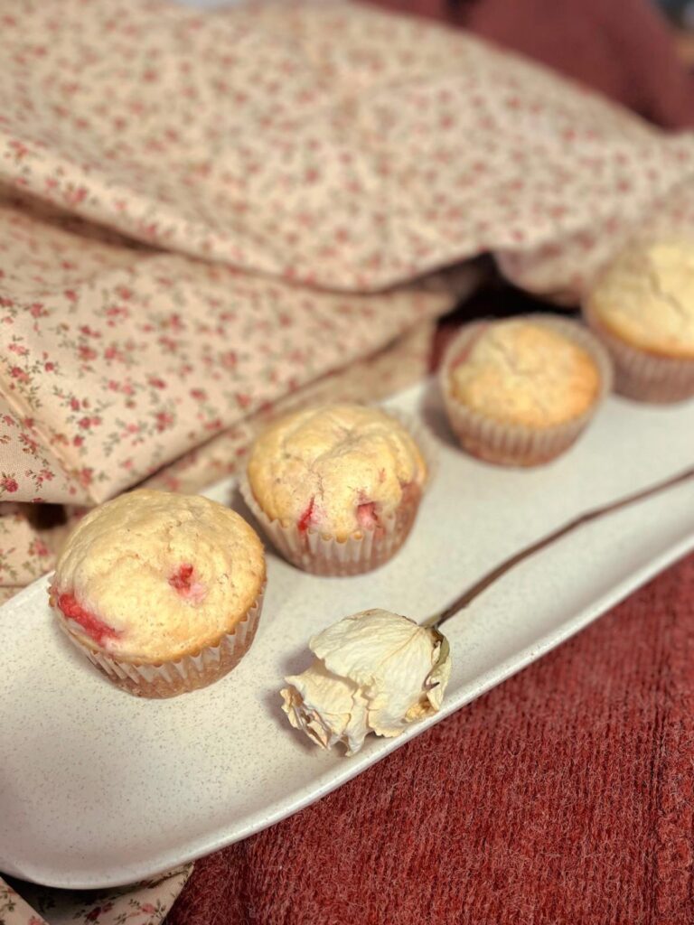 Strawberry vanilla sourdough muffins on a white tray with a dried white rose.