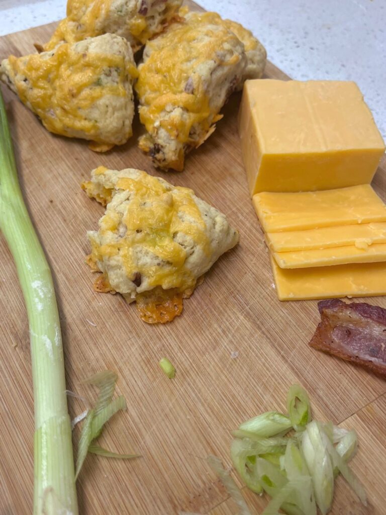 A few scones on a piece of wood with ingredients scattered around.