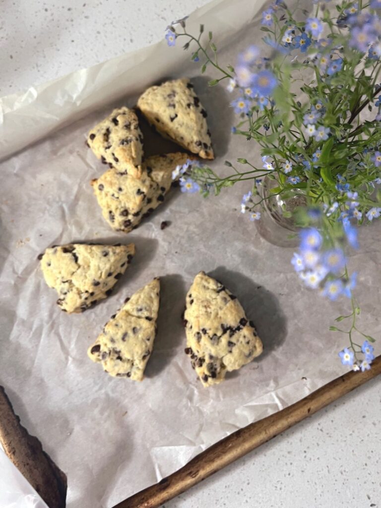 A bouquet of forget me not flowers and some scones in a circle. 