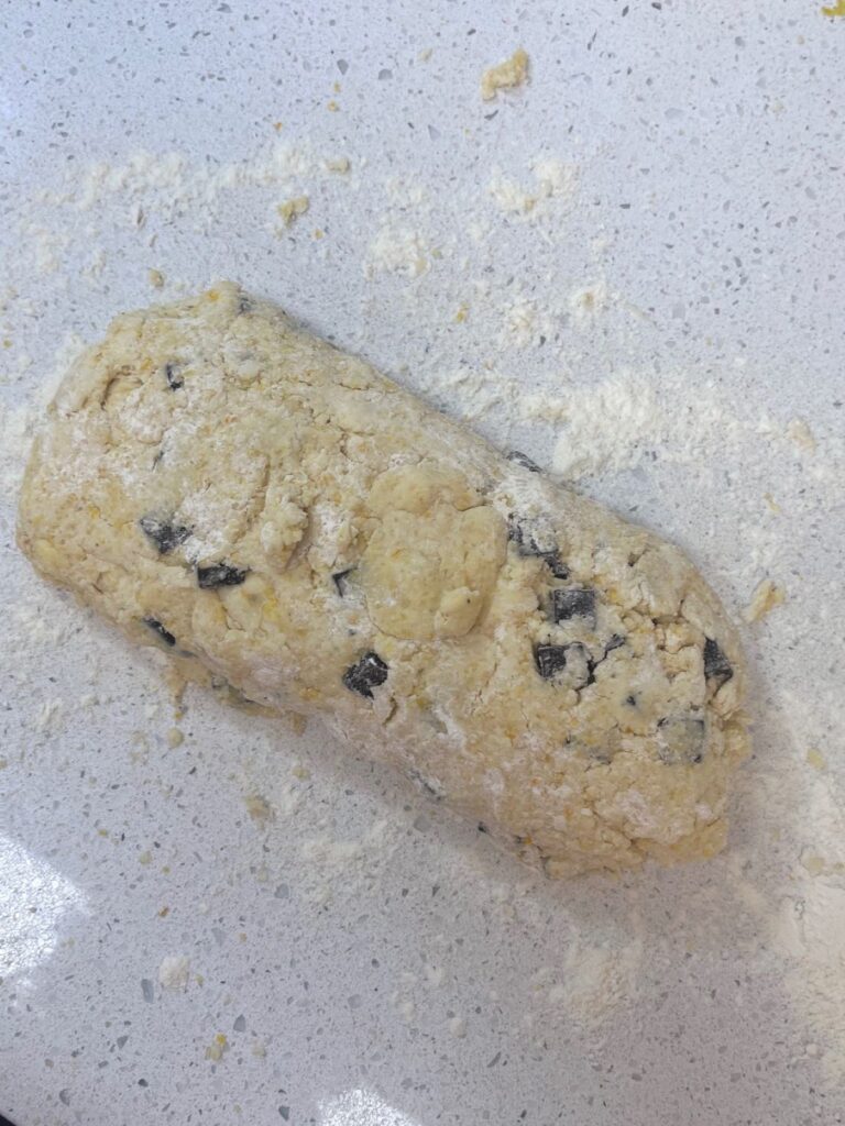 A log of chocolate orange sourdough scones on a lightly floured surface.