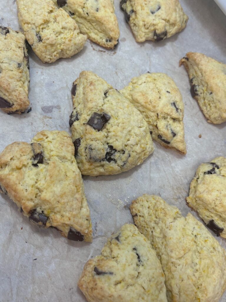 Freshly baked sourdough chocolate orange scones on a piece of parchment paper.