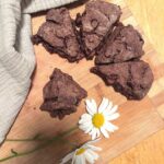 A half circle of double chocolate sourdough scones on a board with a pair of daisies.