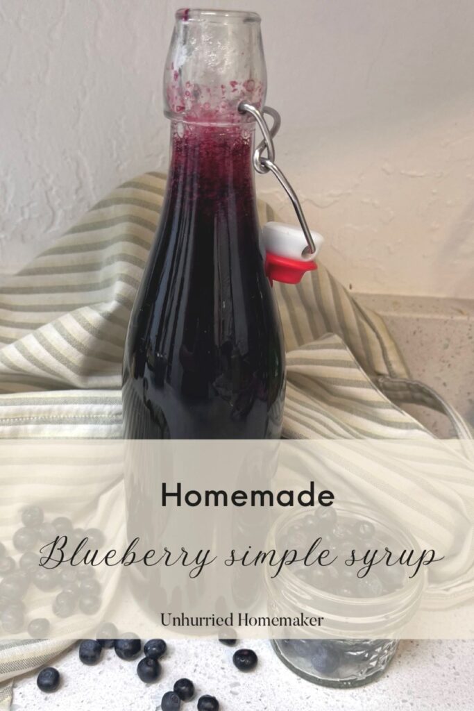 A bottle of homemade blueberry simple syrup with a small jar of blueberries. Unhurried homemaker.
