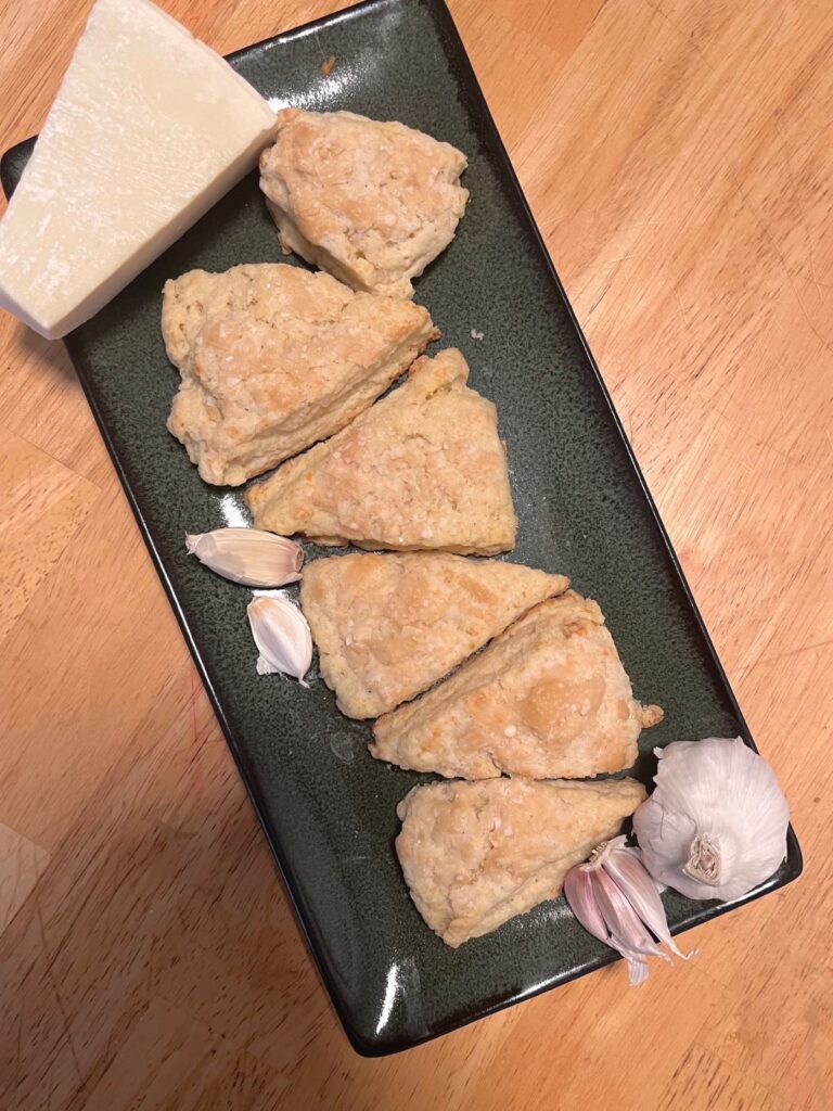 Sourdough scones alternating direction on a long plate with bits of garlic and parmesan around them