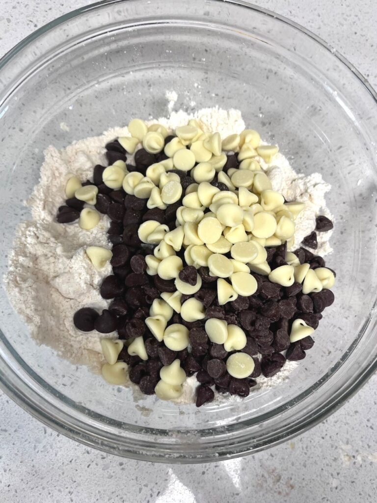 A bowl with dry ingredients and a bunch of chocolate chips dumped on top.