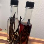 Two bottles of homemade vanilla extract with vanilla beans in them.