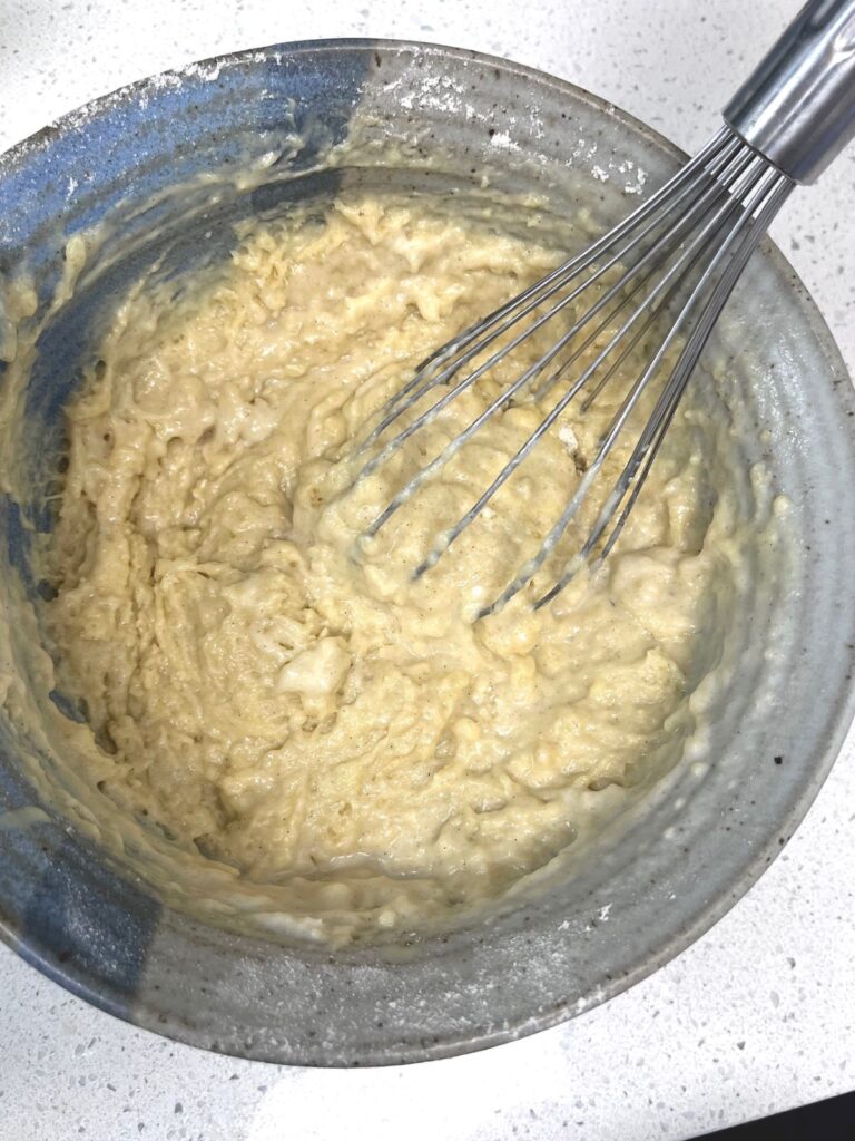Sourdough muffin batter in a bowl with a whisk.