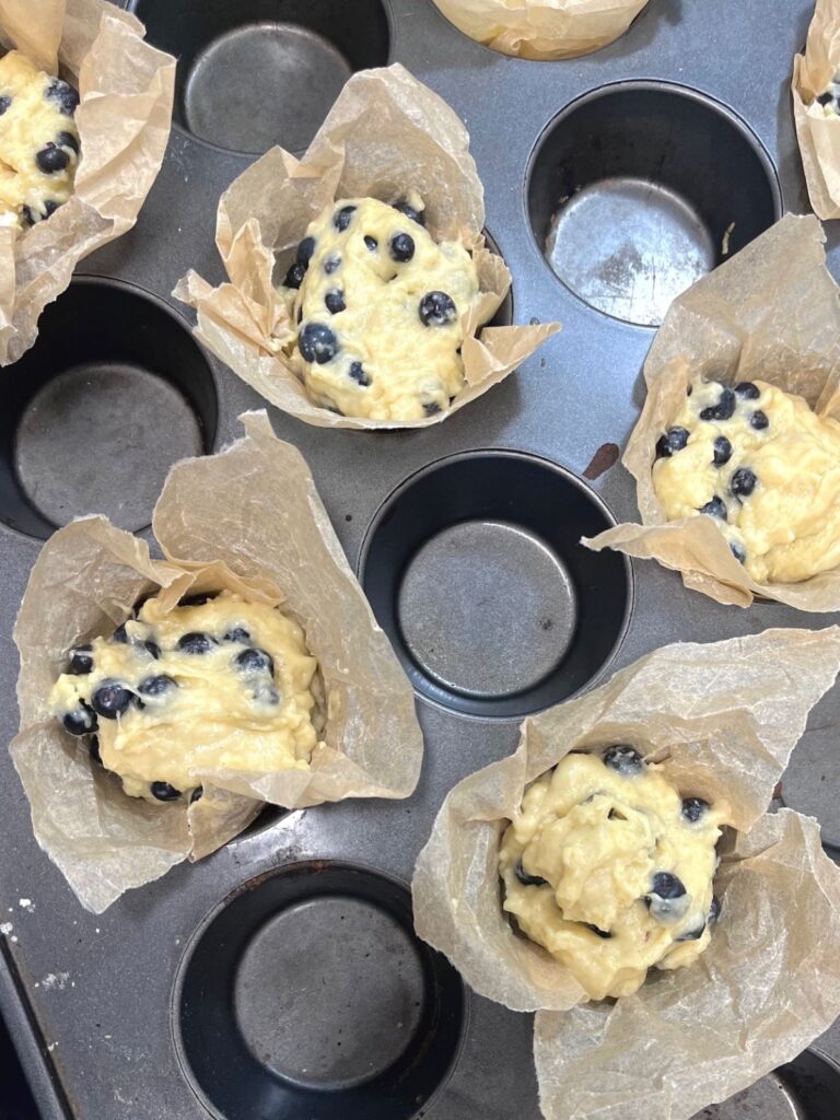 Muffin liners in a muffin tin filled with muffin batter.