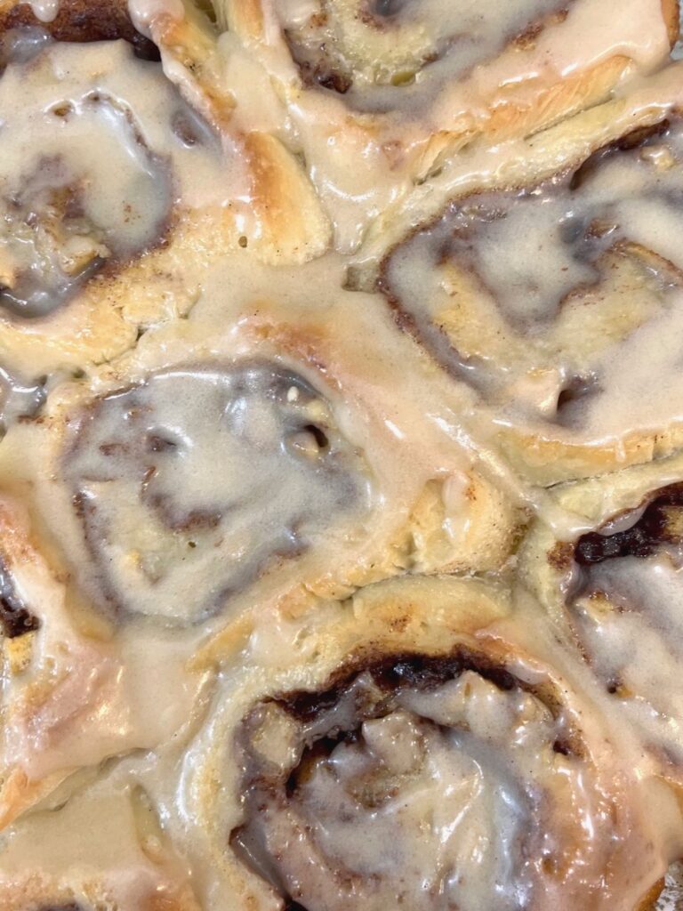 A close up of glazed sourdough apple cinnamon rolls.