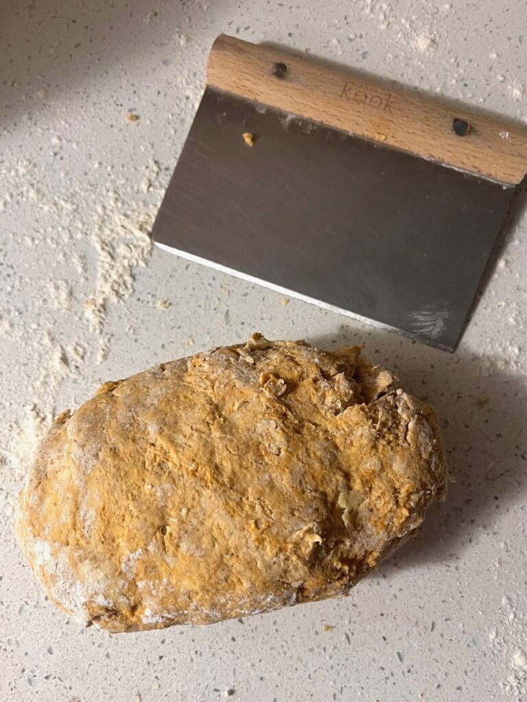 A log of scone dough next to a bench scraper.