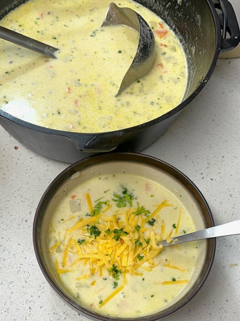 A bowl of soup next to a pot of soup with a ladle.