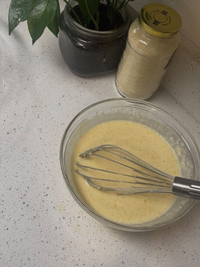 A bowl of wet ingredients with a metal whisk.