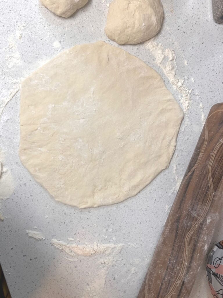 A naan bread rolled out on a countertop.
