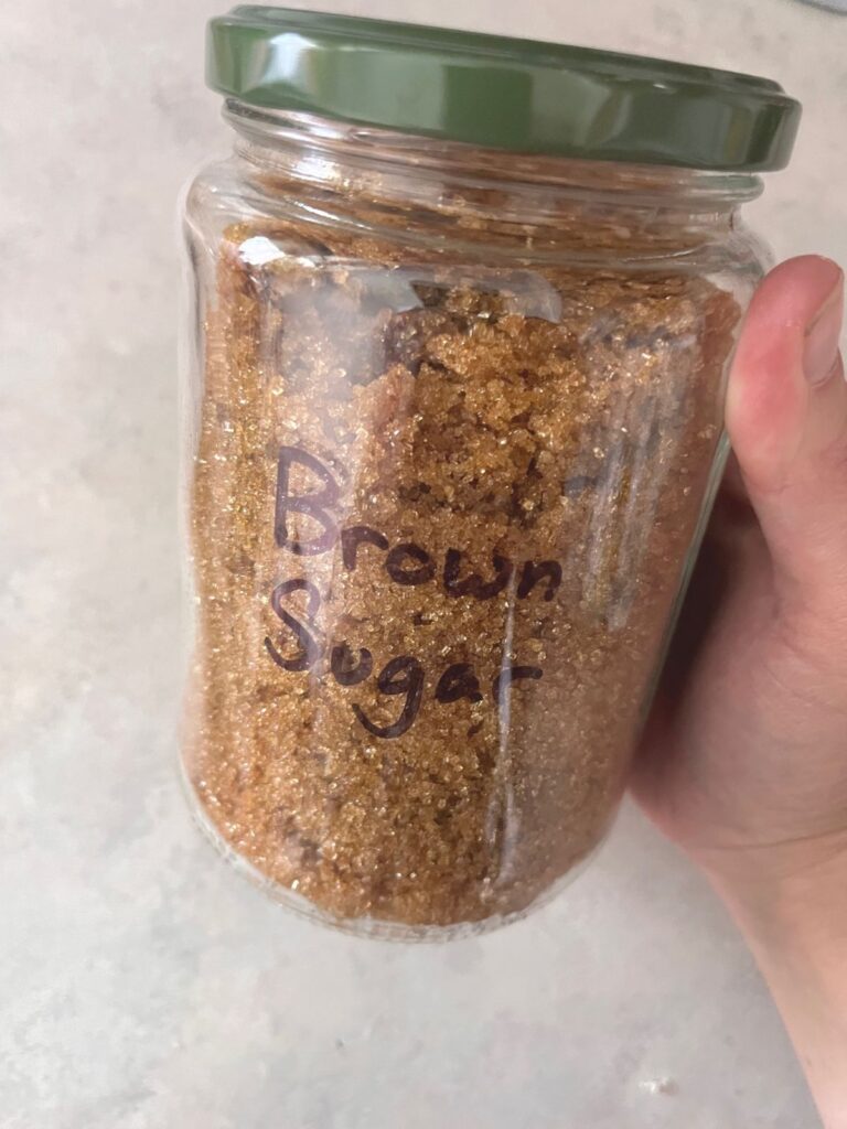 A jar full of brown sugar with a green lid.